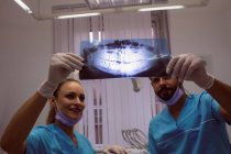 Dentistas discutiendo sobre rayos X en clínica dental - foto de stock