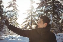 Усміхнений чоловік бере селфі на мобільний телефон взимку — стокове фото