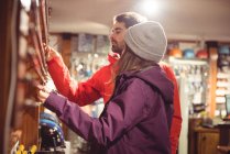 Pareja seleccionando bastón de esquí juntos en una tienda - foto de stock