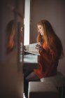 Молодая женщина читает книгу у окна в ресторане — стоковое фото