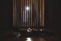 Женщина практикует йогу в темной фитнес-студии с подсветкой — стоковое фото