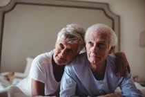 Happy senior couple lying on bed in bed room — Stock Photo