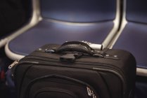 Close-up of black color trolley travel bag against seats in transport — Stock Photo
