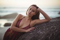 Retrato de mulher bonita apoiando-se na rocha na praia — Fotografia de Stock