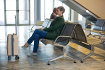 Mujer sentada con equipaje en la sala de espera en la terminal del aeropuerto - foto de stock