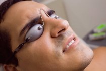 Paciente con gafas de protección láser en la clínica - foto de stock