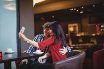 Casal tirando uma selfie usando telefone celular no restaurante — Fotografia de Stock