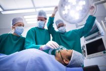Cirurgiões ajustando máscara de oxigênio no paciente no teatro de operação do hospital — Fotografia de Stock