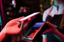 Cliente fazendo pagamento através de telefone inteligente no bar — Fotografia de Stock