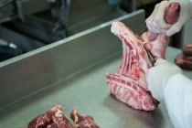 Мясник режет мясо на мясокомбинате — стоковое фото