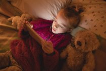 Девушка лежит и с помощью цифрового планшета в спальне дома — стоковое фото