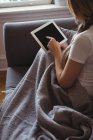 Жінка використовує цифровий планшет на дивані у вітальні — стокове фото