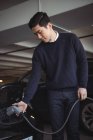 Красивий чоловік заряджає автомобіль на зарядній станції електромобіля — стокове фото