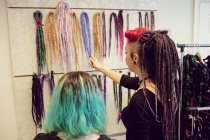 Female shop owner showing dreadlocks to a customer in shop — Stock Photo