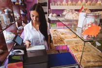 Female shopkeeper using cash register in shop — Stock Photo