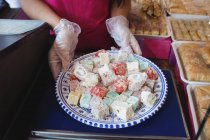 Середина магазину жінок тримає лоток турецьких солодощів за лічильником в магазині — стокове фото