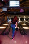 Vista posteriore della donna che gioca a bowling nel bar — Foto stock