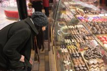 Frau schaut sich Desserts an Desserttheke in Bäckerei-Theke an — Stockfoto