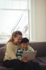 Mutter und Sohn nutzen digitales Tablet im heimischen Wohnzimmer — Stockfoto