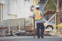 Vista traseira do trabalhador da construção que transporta madeira no estaleiro de construção — Fotografia de Stock