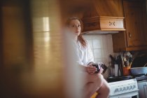 Mulher sentada e tomando café na cozinha em casa — Fotografia de Stock