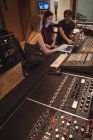 Аудіоінженери використовують ноутбук біля звукового мікшера в музичній студії — стокове фото