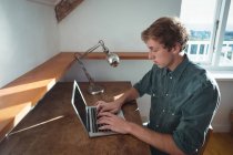 Человек сидит за столом и использует ноутбук в кабинете — стоковое фото