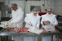Bouchers emballant des saucisses à l'intérieur de l'usine de viande — Photo de stock