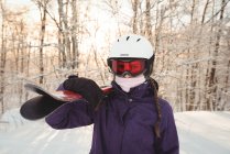 Retrato de mujer en ropa de esquí sosteniendo esquís en su hombro - foto de stock