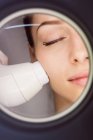 Medico che dà massaggio facciale al paziente attraverso il sollevamento sonico in clinica — Foto stock