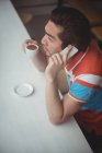 Uomo che parla al cellulare mentre prende un caffè in caffetteria — Foto stock
