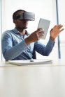 Ejecutivo empresarial que utiliza auriculares de realidad virtual y tableta digital en la oficina - foto de stock