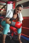 Portrait of tired female boxer sitting in the ring in fitness studio — Stock Photo