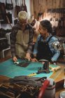 Artesanas discutiendo sobre una pieza de cuero en el taller - foto de stock