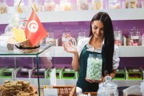 Жінка-магазин тримає банку турецьких солодощів за лічильником в магазині — стокове фото