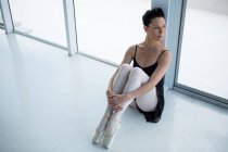 Bailarina pensativa sentada en el suelo en el estudio de ballet - foto de stock