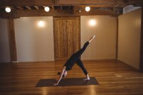 Mulher fazendo exercício de perna enquanto pratica ioga no estúdio de fitness — Fotografia de Stock