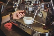 Camarera preparando una taza de café en la cafetería - foto de stock