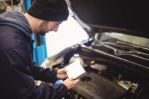 Mechaniker mit digitalem Tablet am Auto in Werkstatt — Stockfoto