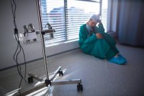 Cirujano femenino ensangrentado sentado en el pasillo del hospital - foto de stock