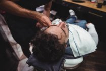 Client getting beard shaved in barber shop — Stock Photo