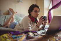 Schöne Frau mit Laptop, während Kaffee auf dem Bett zu Hause — Stockfoto