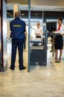 Flughafensicherheitsmitarbeiter mit Passagieren beim Gang durch den Körperscanner im Flughafenterminal — Stockfoto