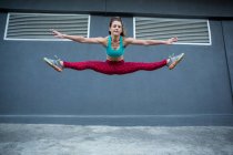 Женщина прыгает, практикуя паркур на улице — стоковое фото