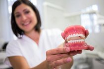 Руки женщины-стоматолога держат набор протезов в клинике — стоковое фото