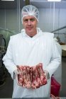 Portrait of butcher holding meat in meat factory — Stock Photo