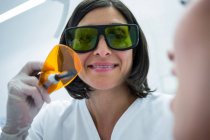 Dentista examinando dentes jovens de pacientes com luz de cura dentária na clínica — Fotografia de Stock