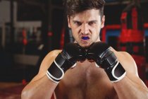 Boxer with gumshield performing boxing stance in fitness studio — Stock Photo