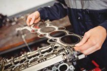 Mid-section of female mechanic checking a car parts in repair garage — Stock Photo