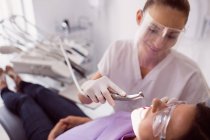 Dentista examinando paciente femenina en clínica - foto de stock